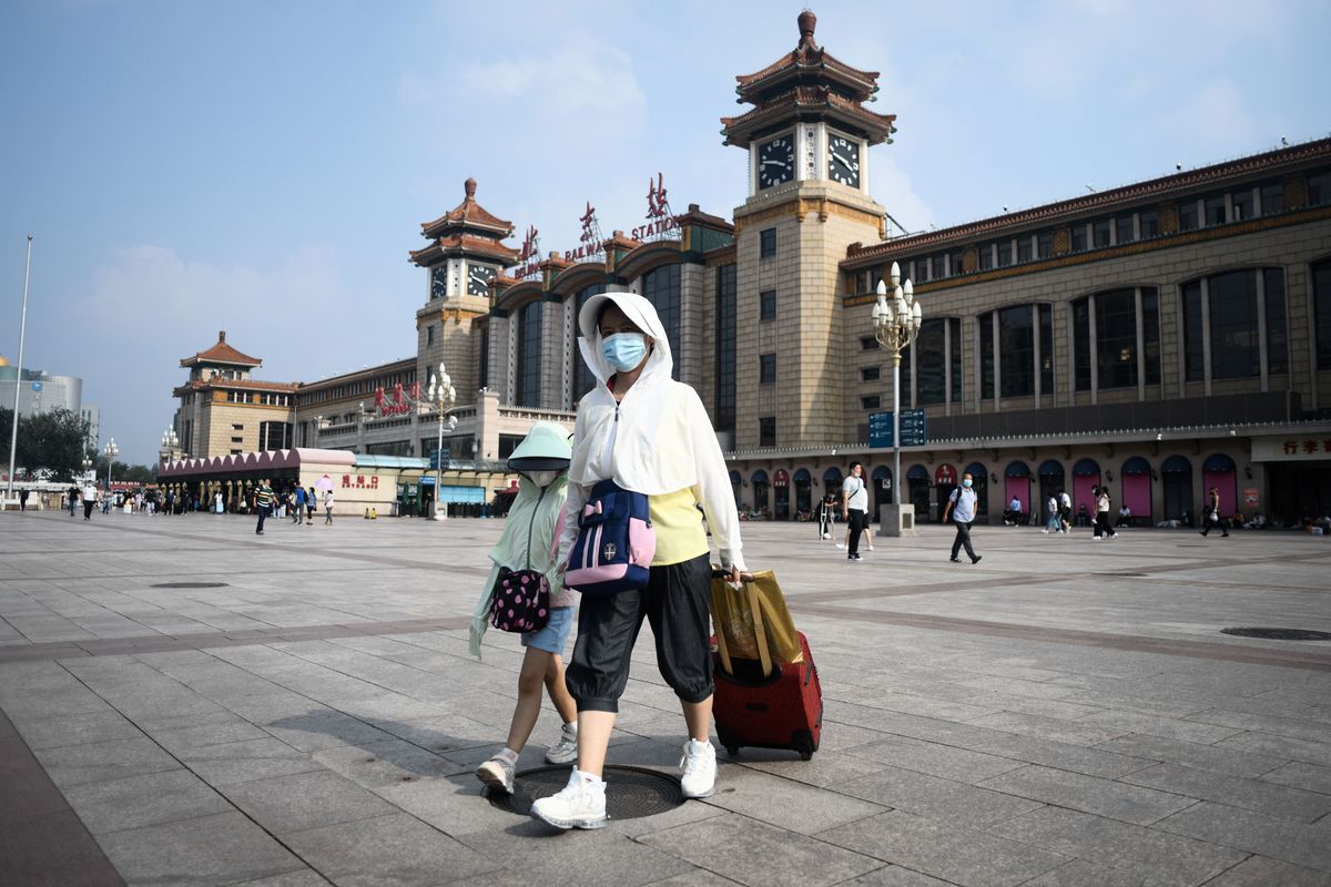 2021年8月7日，北京市當局暫停除天津、河北之外其它省市的進出京長途客運班線和旅遊包車業務。圖為2021年8月4日一名婦女帶著一名兒童抵達北京火車站。（WANG ZHAO/AFP via Getty Images）