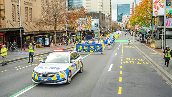 2022年6月25日國際反酷刑日前夕，澳紐150多名法輪功學員在奧克蘭皇后大街遊行。圖為警車為法輪大法天國樂團開路。（袁弘/大紀元）