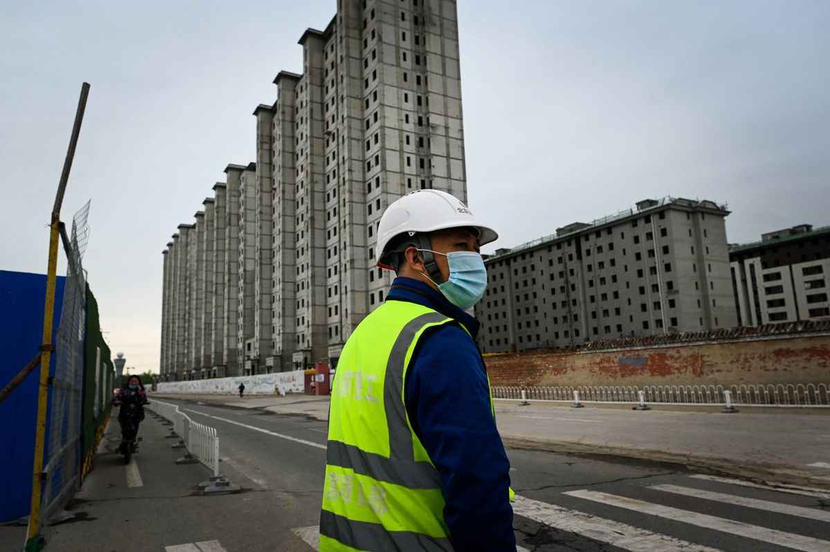 2022年4月26日，北京一個建築工地外，一名工人正準備過馬路。（WANG ZHAO/AFP via Getty Images）