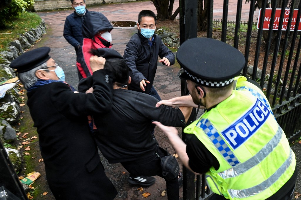 2022年10月16日，中共二十大之際，港人在曼城中領管外進行抗議活動。圖片中，可以看到幾個中領館的人用力將一名香港男子拖進領館地盤，那名「白髮男」揪住港人的頭髮，而一名英國警察則奮力把港人救出。 （Matthew Leung/THE CHASER NEWS/AFP）