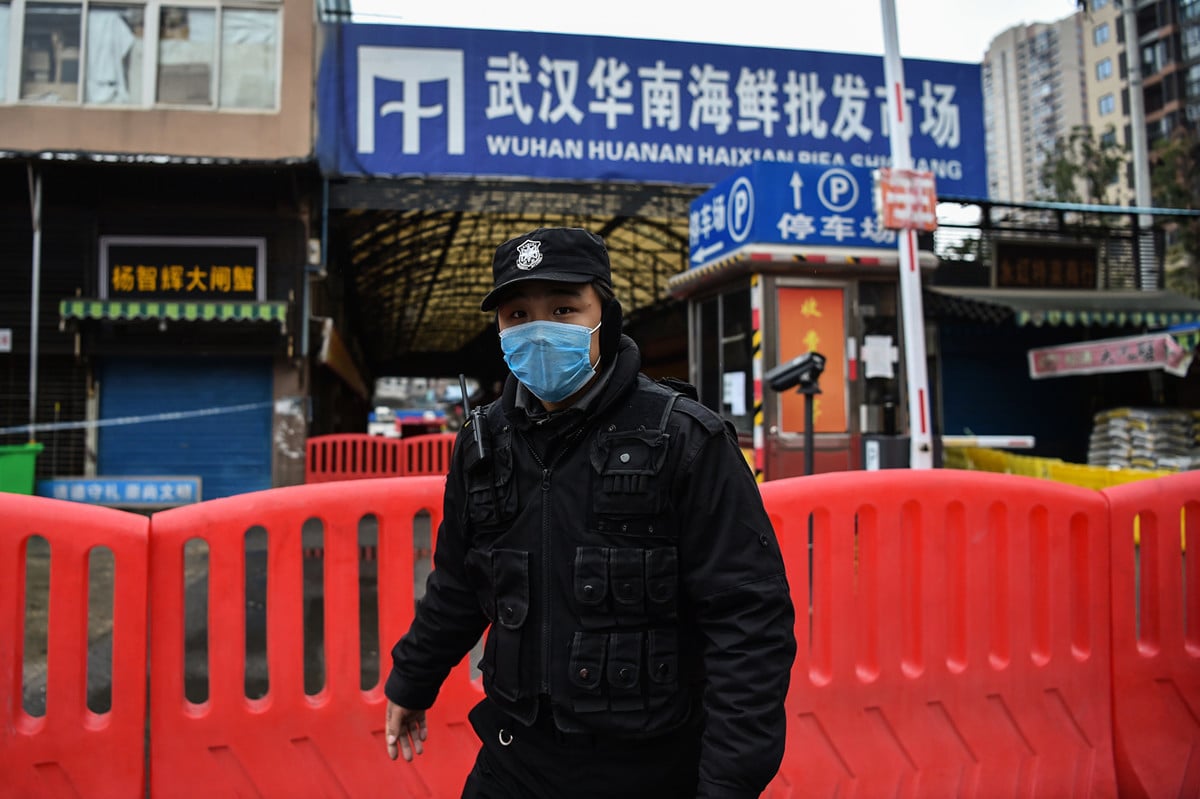 中共官媒引述一項最新研究報道說，中共病毒並非源自武漢華南海鮮市場，美國參議員據此要求北京給答案。圖為1月25日一名公安站在華南市場外。（Hector RETAMAL/AFP）