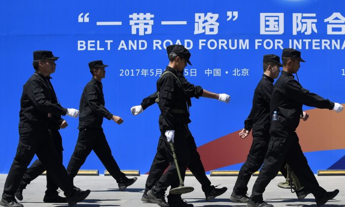 2017年5月14日至15日，首屆「一帶一路」國際合作高峰論壇在北京舉行。圖為5月13日，保安走過該論壇的宣傳牌。（Wang Zhao/AFP via Getty Images）