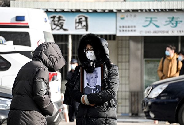 2022年12月20日，在北京爆發新一輪疫情期間，一名婦女在北京火葬場持著親人的遺像。（Noel Celis/AFP）