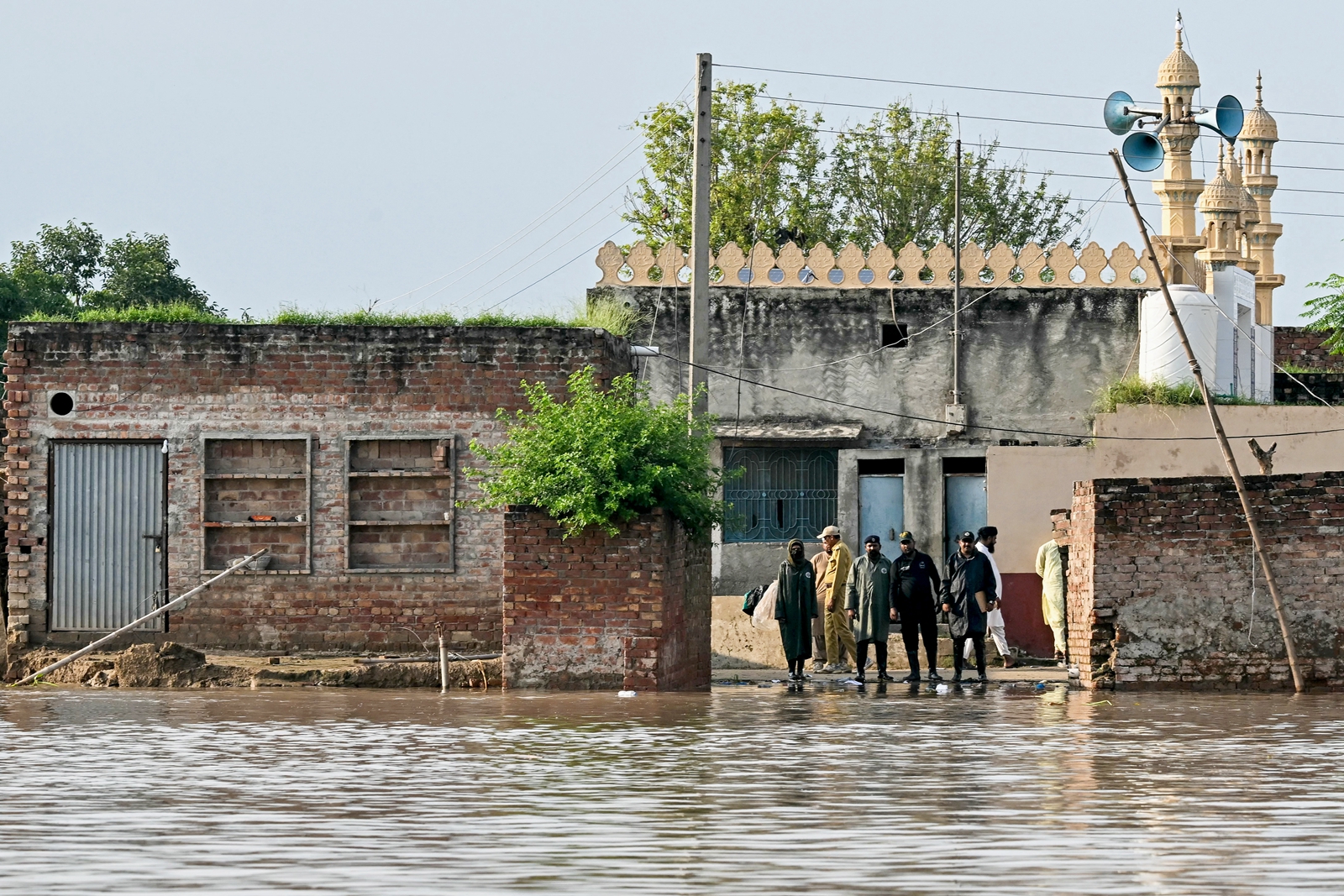2025年9月3日,大雨導致薩特累季河(Sutlej River)水位上升,幾位官員站在旁遮普省卡蘇爾區(Kasur district)被洪水淹沒的沿岸邊。(Farooq Naeem/AFP via Getty Images)