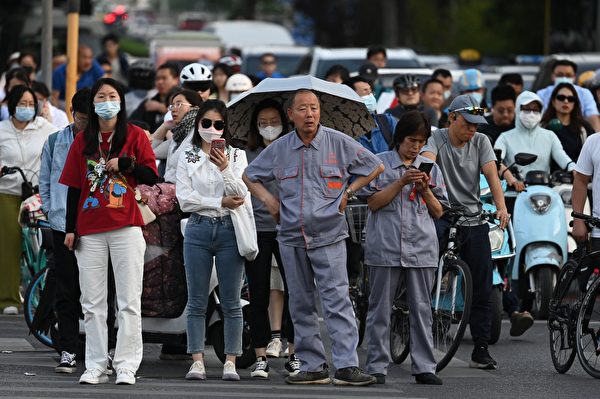 2023年5月22日，北京居民正準備過一個路口，有的戴著口罩，有的沒有戴口罩。（Greg Baker/AFP via Getty Images）