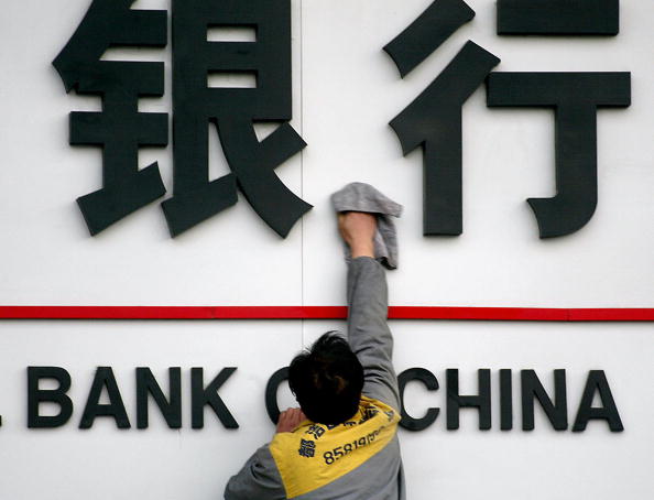 中國金融市場問題越加嚴重，出現不穩定現象。圖為一個清潔工人在清潔某銀行招牌。（Getty Images）
