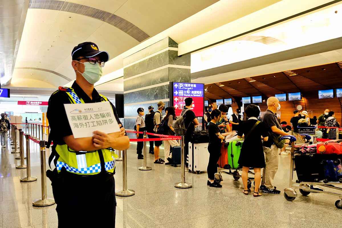 台灣航警局近日持續派人在桃園國際機場舉牌，提醒民眾慎防海外高薪打工詐騙。（中央社）