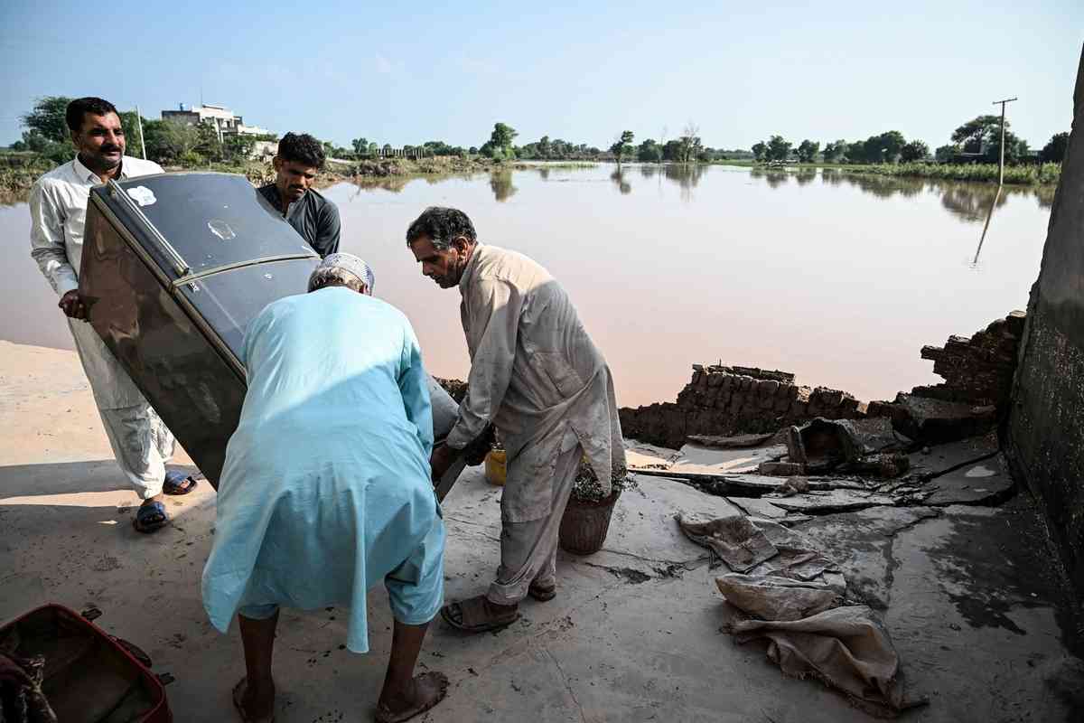 2025年8月28日,巴基斯坦旁遮普省,沃濟拉巴德區(Wazirabad District)Chak Ali Sher村遭洪水襲擊後,村民將被水浸泡的雪櫃抬到戶外晾晒。(Aamir Qureshi/AFP via Getty Images)