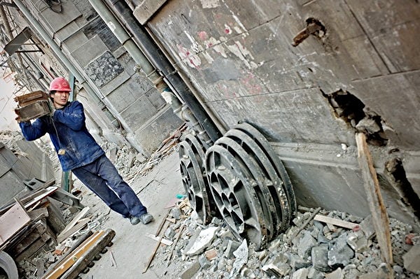 上海世博會製造出1萬8000個拆遷戶。圖為2010年1月18日，上海世博會前夕進行的整修工程，一名工人搬運拆除的舊建築碎片。（Philippe Lopez/AFP）