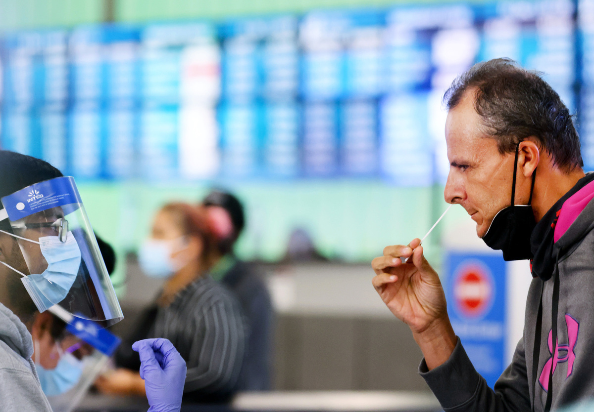2021年12月3日，加州洛杉磯國際機場（LAX），一名來自意大利的乘客COVID-19檢測點收集鼻拭子。 （Mario Tama/Getty Images）