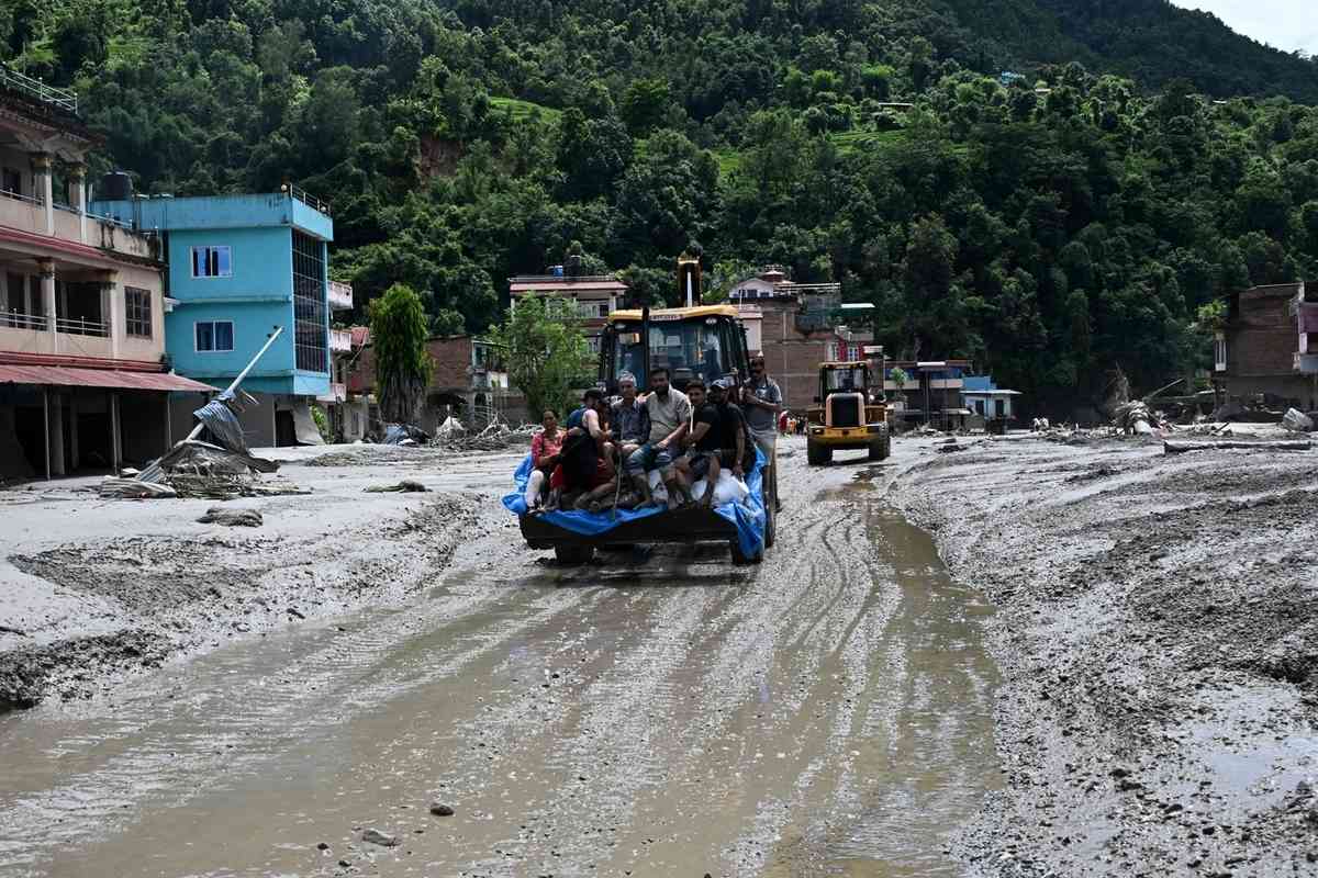 2026年8月27日，在尼泊爾努瓦科特縣（Nuwakot）德夫加特（Devghat）發生山洪的第二天，救援人員使用推土機運送受困的災民。（Prakash Mathema/AFP via Getty Images）