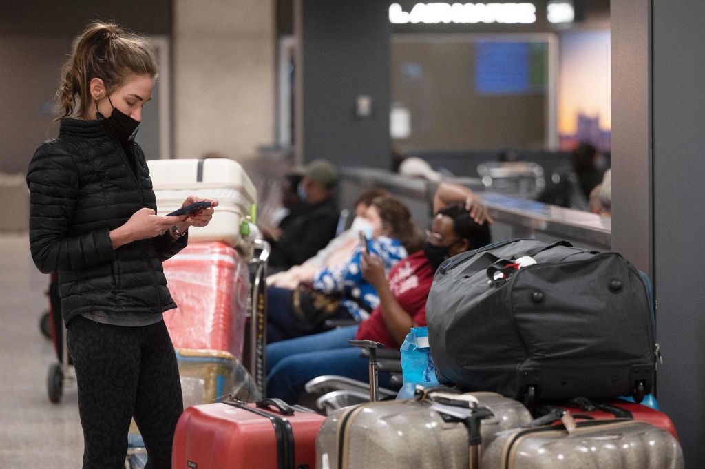 由於南非發現了最新病毒變種，很多航空公司取消了相關航班，愛爾蘭公布了對非洲七國的旅行建議。圖為一名乘客在美國一家國際機場查看手機。（JIM WATSON/AFP via Getty Images）