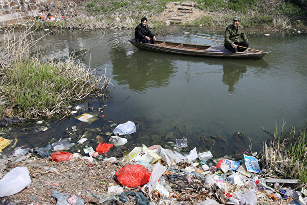 圖為江蘇省宜興市村民在一條被嚴重污染的河流上釣魚。（MARK RALSTON/AFP/Getty Images）