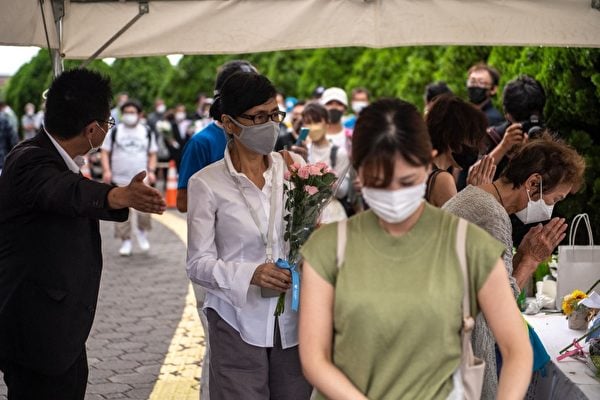 2022年7月9日，人們排隊在前首相安倍遭襲場所附近的臨時紀念點上獻花。（Philip Fong/AFP）