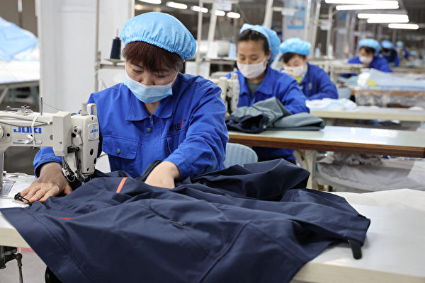 2022年1月27日，山東省濱州一家工廠的工人在生產防護服。（China OUT/AFP）