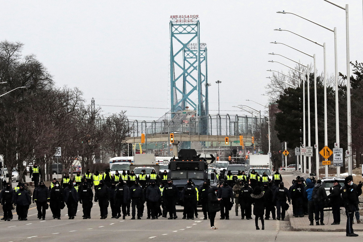 2022年2月13日，加拿大安大略省溫莎市，警察聚集在一起，清除封鎖大使橋的反疫苗令抗議人士。加拿大安大略省溫莎市，警方加派警力，聚集起來清除反對Covid-19疫苗令的抗議人士。現場有50多輛汽車，包括一輛裝甲車。（JEFF KOWALSKY/AFP via Getty Images）