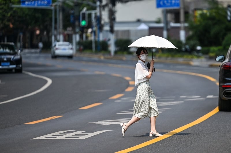 2022年8月11日，一名帶著口罩的女子在上海街頭行走。（Hector Retamal/AFP via Getty Images）