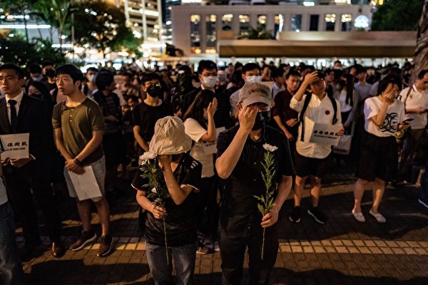 2019年8月30日晚上8點，香港民眾在中環和平紀念碑舉辦重光紀念日默站活動，參與民眾做出掩右眼手勢。（Anthony Kwan/Getty Images）
