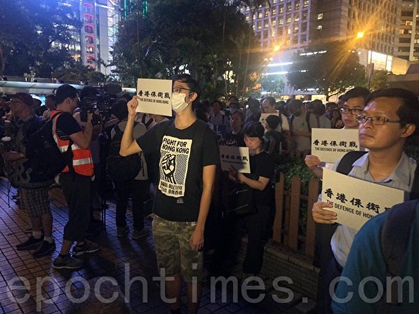 2019年8月30日晚上8點，香港民眾在中環和平紀念碑舉辦重光紀念日默站活動。圖為民眾手持「香港保衛戰」標語。（梁珍／大紀元）
