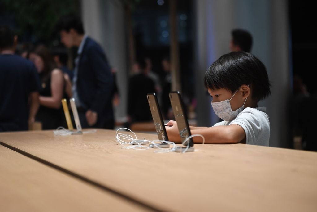 2018年11月9日一名兒童在泰國曼谷的一家蘋果手機門店內使用手機。（LILLIAN SUWANRUMPHA/AFP/Getty Images）