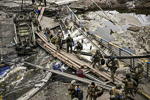 2022年3月13日，烏克蘭士兵走在烏克蘭基輔西北部伊爾平市（Irpin）附近一座被毀橋樑旁的臨時小徑上。（Aris Messinis/AFP via Getty Images）