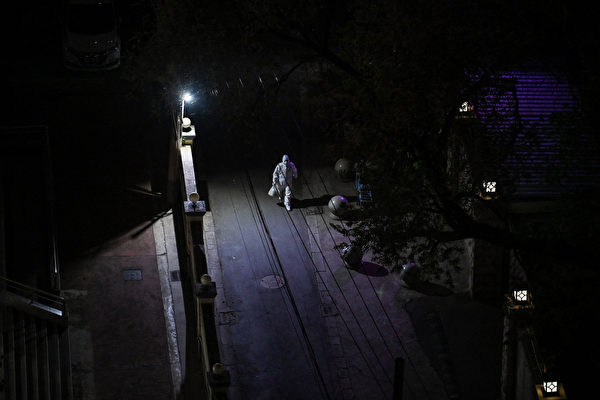 2022年4月10日夜裏，上海靜安區一名穿防護裝備的工人在街上行走。（Hector Retamal/AFP）