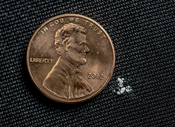  兩毫克致命劑量的芬太尼粉末的插圖，旁邊是一美分硬幣的對比。（DEA）