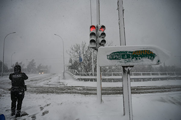 2022年1月24日，希臘雅典，國家高速公路被白雪覆蓋，一名警察站在道路的交岔口。（Aris Messinis/AFP）