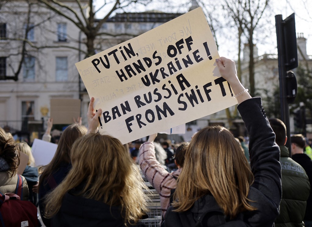 ​2022年2月26日，在俄羅斯入侵烏克蘭後，抗議者在俄羅斯駐倫敦大使館外參加抗議集會，舉著一張標語牌，呼籲禁止俄羅斯加入SWIFT銀行系統。（Tolga Akmen/AFP）