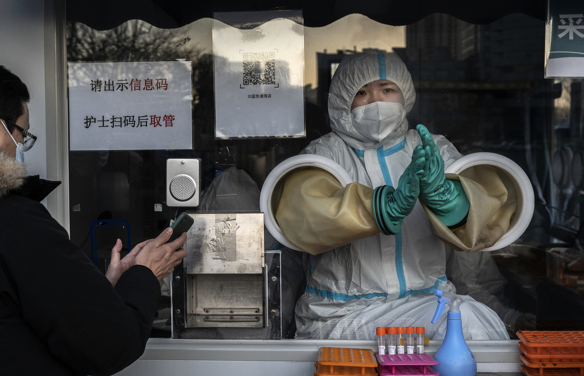 圖為中國的一家診所，一名醫務人員戴著防護手套，為客戶進行核酸測試，測試前要求掃瞄健康碼。（Kevin Frayer/Getty Images）