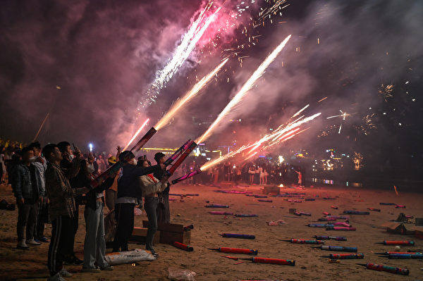 2023年元旦，中國多地民眾打破中共的煙花爆竹「禁燃令」，因此發生警民衝突。圖為2023年1月1日，人們在中國海南省三亞市後海的一個海灘上放煙花慶祝新年。（Hector Retamal/AFP）
