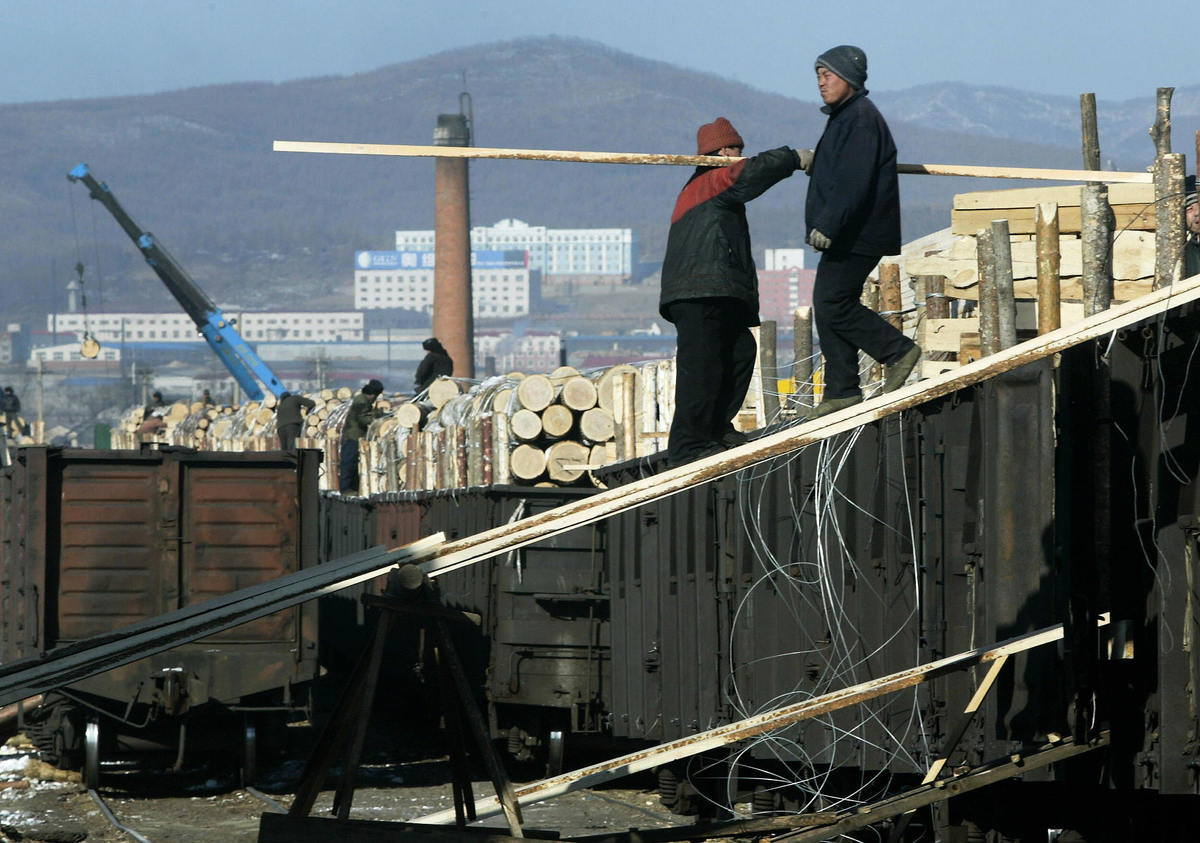 2003年1月13日，在中國東北黑龍江省的中俄邊境城市綏芬河，中國工人在一家木材廠接收來自俄羅斯邊境的木材。（FREDERIC J. BROWN/AFP via Getty Images）