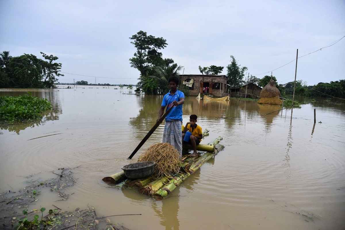 2025年6月3日,印度阿薩姆邦霍賈伊區(Hojai district)發生嚴重洪澇,一名男子用小船載著另一名男子和物品轉移至安全地帶。(Anuwar Hazarika/Middle East Images/AFP via Getty Images)