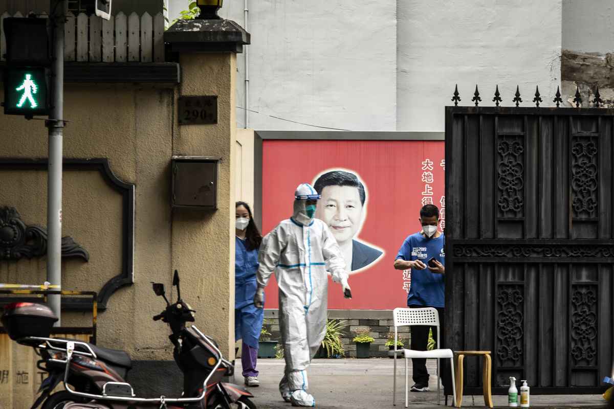 2022年6月10日，上海黃浦區瑞金二路街道執法機構的門口，工作人員穿戴全身防護裝備走過習近平的畫像。（Qilai Shen/Bloomberg via Getty Images）