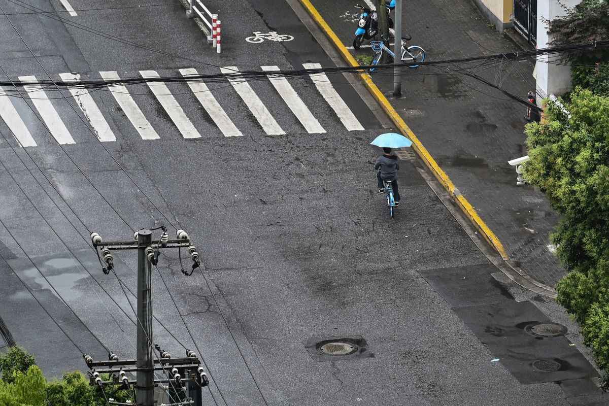 2022年5月24日，一名上海市民在空蕩蕩的街道上騎行。（HECTOR RETAMAL/AFP via Getty Images）