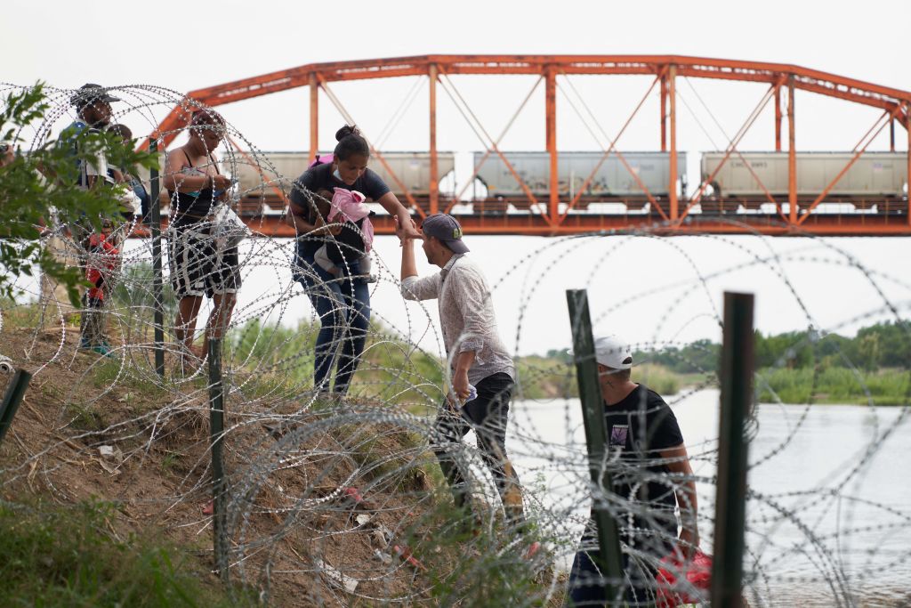 圖為2022年5月22日，非法穿越里奧格蘭德河的移民沿著德薩斯州邊境城市伊格爾帕斯（Eagle Pass）的鐵絲網行走。（ALLISON DINNER/AFP via Getty Images）