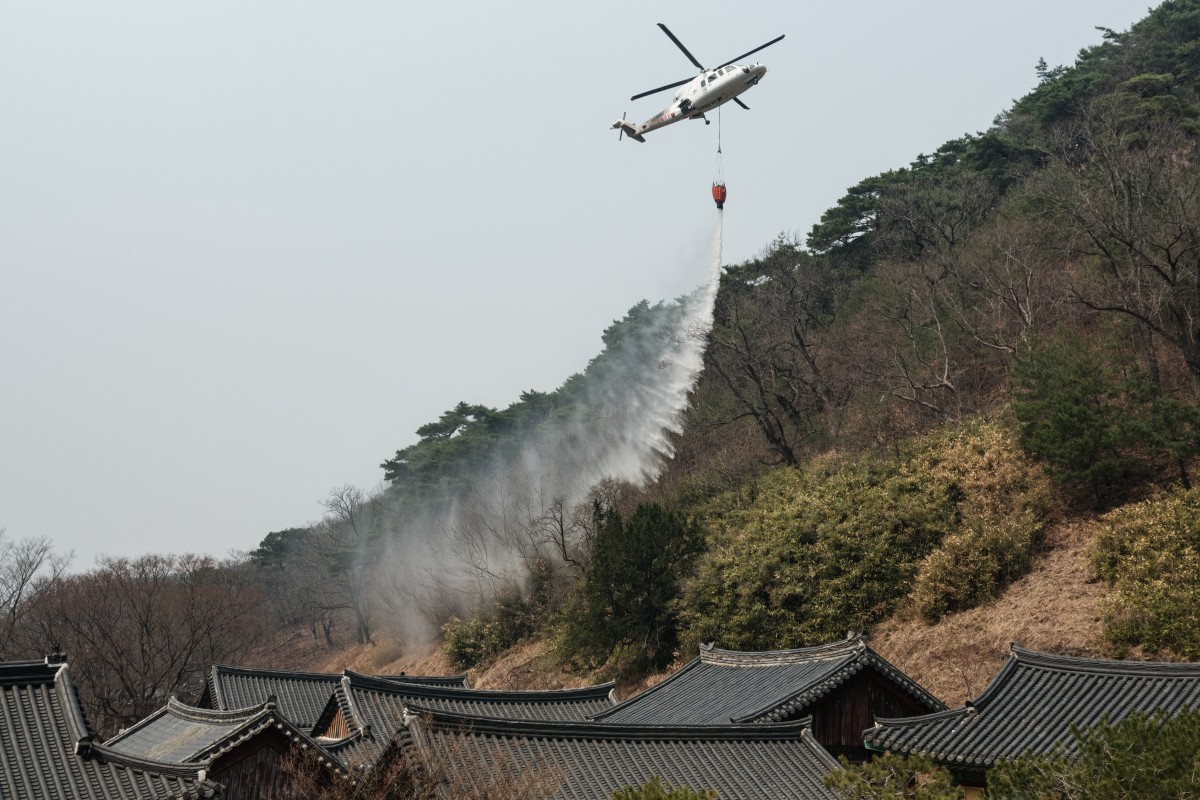 2025年3月25日,南韓義城,一架直升機在高雲寺(Gounsa Temple)附近投放水源,預防山火可能蔓延至寺院。南韓官員指出,隨著乾燥多風的天氣加劇火勢,山火在夜間進一步惡化,成為該國史上最嚴重的火災之一。(YASUYOSHI CHIBA/AFP)