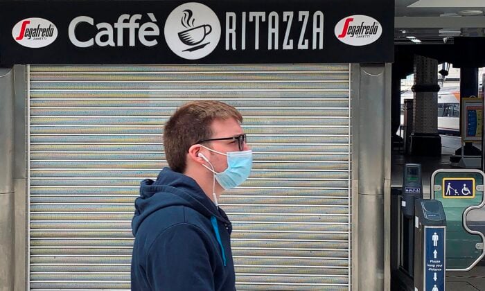 2020年7月1日，在倫敦的一個火車站，一名戴著口罩的行人走過一家關門歇業的Caffe Ritazza咖啡和食品店。（Daniel Leal-Olivas/AFP via Getty Images）