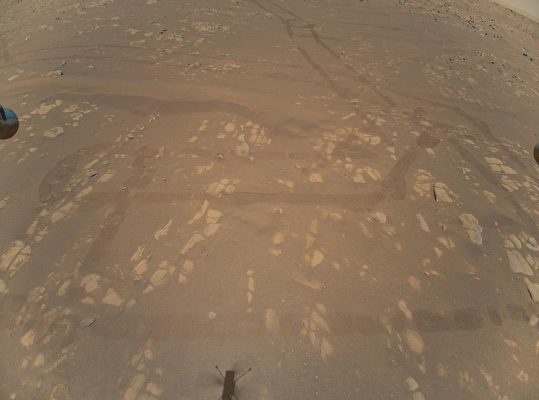 「創新號」（Ingenuity）在第二次飛行時拍攝了它的第一張彩色航空圖像。這架無人機在離地面約五米（16呎）的地方盤旋，傾斜並橫向移動2米（6呎），然後返回到它起飛的地方。在下面的火星表面可以看到「毅力號」的足跡和「創新號」的陰影。（NASA/JPL-CALTECH）