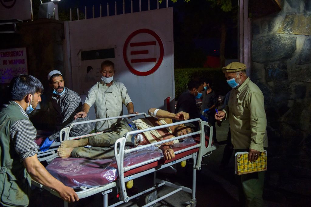 2021年8月26日，在阿富汗喀布爾機場外發生爆炸襲擊。圖為醫務人員正將一名受傷男子抬上擔架。（WAKIL KOHSAR/AFP via Getty Images）