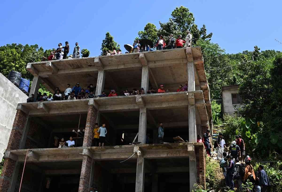 2026年8月27日，在尼泊爾努瓦科特縣（Nuwakot）特里蘇里（Trishuli）發生山洪的第二天，居民站在未完工建築的上層和屋頂避難。（Ritesh Shukla/Getty Images）