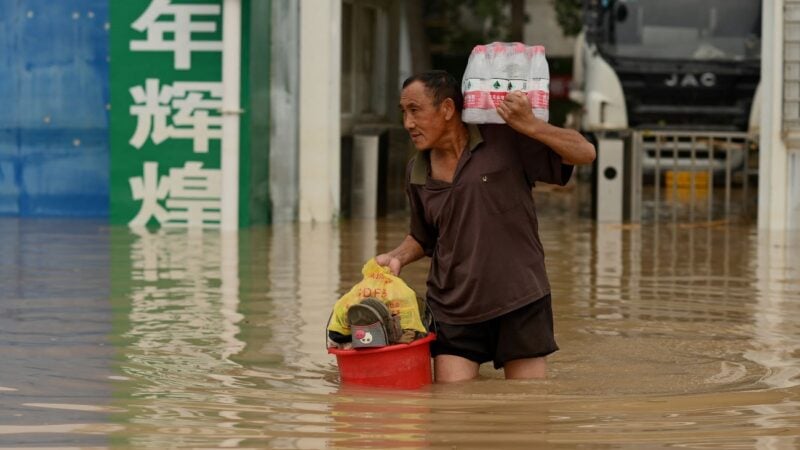 2021年7月20日，河南鄭州的人們在暴雨中涉水走過街道。（NOEL CELIS/AFP via Getty Images）