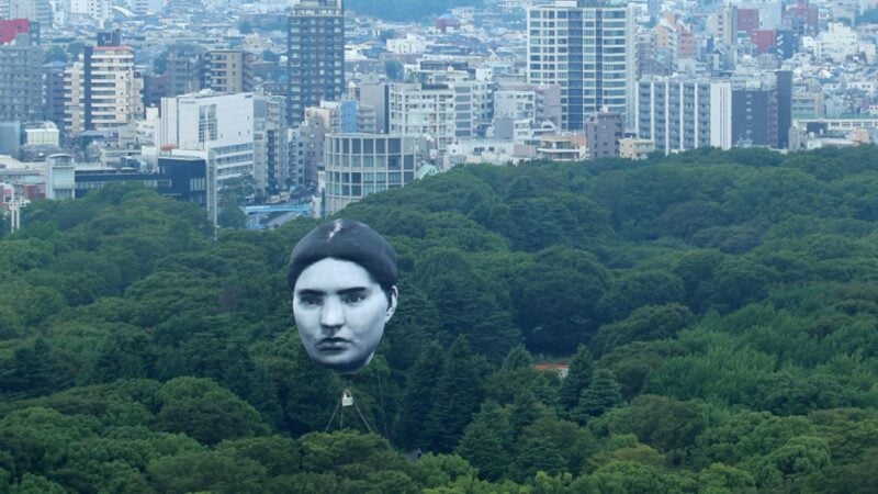7月16日早上，東京上空突然漂浮著一個神秘的「大臉」，足有6層樓高。人們紛紛驚呼「這是誰？」（STR/JIJI PRESS/AFP via Getty Images）