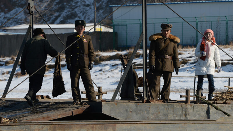 2013年12月15日，北韓士兵在一艘駁船旁守衛，該駁船用於將貨物和人員運送到中國丹東附近的北韓島嶼。（MARK RALSTON/AFP via Getty Images）