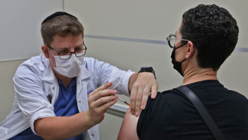 2021 年 8 月 20 日，在以色列耶路撒冷一個衛生服務中心，一名衛生工作者為一名男子注射第三劑輝瑞COVID-19 疫苗。（AHMAD GHARABLI/AFP via Getty Images）