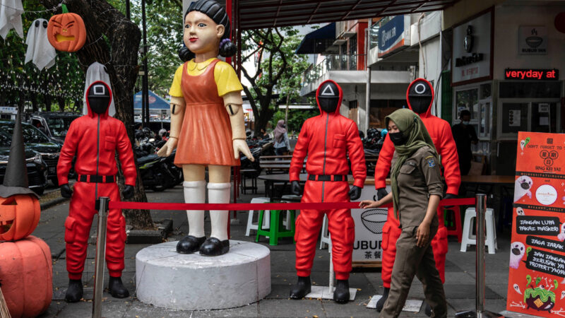 2021 年 10 月 21 日，一名婦女路過印度尼西亞東爪哇省泗水市美食廣場的《魷魚遊戲》角色雕像。（JUNI KRISWANTO/AFP via Getty Images）