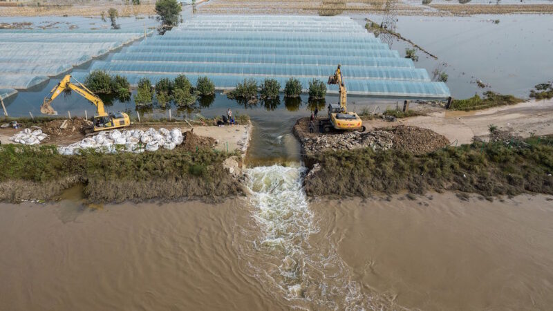 2021年 10月 11日，在中國北部山西省晉中市介休的洪水氾濫地區，救援人員用挖掘機挖掘溢洪道以釋放洪水。（AFP via Getty Images）