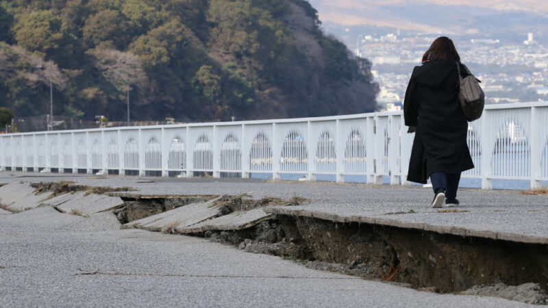 2022年1月22日，日本西南部太平洋沿岸發生地震後，一名婦女在大分縣開裂的道路上行走。（STR/JIJI PRESS/AFP via Getty Images）