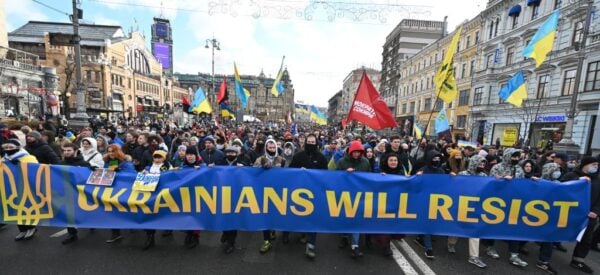 2022年2月12日，在基輔舉行的集會上，示威者一邊喊著口號，一邊在一面寫有「烏克蘭人將抵抗」的旗幟後面行進。（SERGEI SUPINSKY/AFP via Getty Images）
