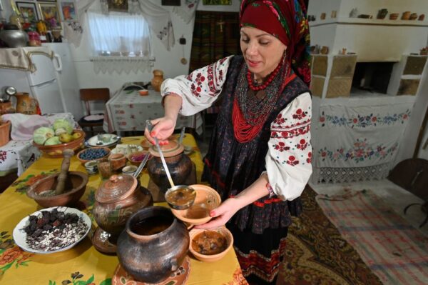 圖為，2020年11月26日，在波爾塔瓦州的奧皮什尼亞村，烏克蘭民族學家和歷史學家奧萊娜-謝爾班（Olena Shcherban）身著烏克蘭傳統服裝和頭飾，在柴火爐中用粘土鍋煮羅宋湯，她研究羅宋湯，並收藏了365份來自烏克蘭各地的獨特菜譜。（GENYA SAVILOV/AFP via Getty Images）